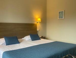 a bed with two blue pillows on top of it at Grand Hôtel De Calvi in Calvi
