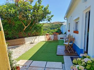 a patio with green grass and a table and chairs at Casa com pátio - São Lourenço (Ericeira) in Casais de São Lourenço