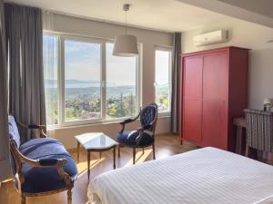 a bedroom with a bed and two chairs and windows at Yaylı Apart in Masukiye