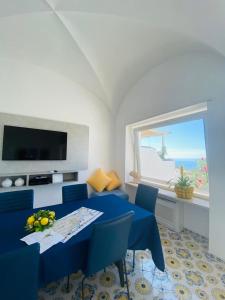 een woonkamer met een blauwe tafel en stoelen en een raam bij Villa La Panoramica 3 camere 3 bagni in Capri