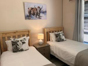 2 camas en un dormitorio con una foto de un toro en Clarens The Paddocks 21, en Clarens