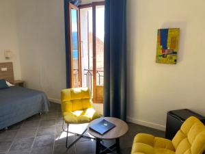 a bedroom with a bed and a yellow chair and a table at Grand Hôtel De Calvi in Calvi