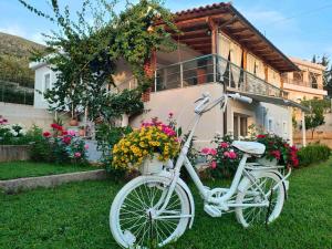 een witte fiets geparkeerd voor een huis met bloemen bij DreamAdes House in Dhërmi