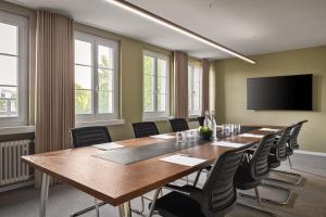 une salle de conférence avec une grande table et des chaises en bois dans l'établissement b-smart hotel Widnau, à Widnau