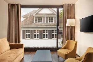 a living room with a large window and a couch and chairs at b-smart hotel Widnau in Widnau +21 photos