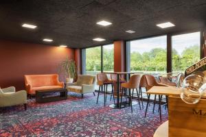una sala d'attesa con sedie, tavolo e finestre di b-smart hotel Widnau a Widnau