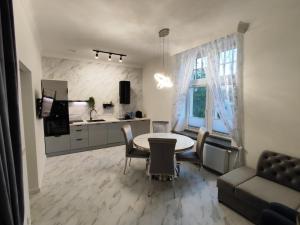 a living room with a table and chairs and a kitchen at Apartament Jak w banku in Kłodzko