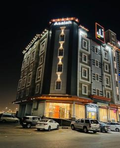 a large building with cars parked in a parking lot at اصالة الشروق للشقق المخدومه in Al Khobar