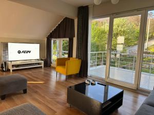 sala de estar con TV y silla amarilla en Yaylı Apart en Masukiye