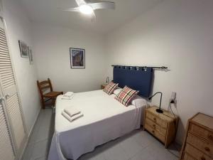een slaapkamer met een groot wit bed en een stoel bij Apartamentos Bellavista Gomera in Playa de Santiago