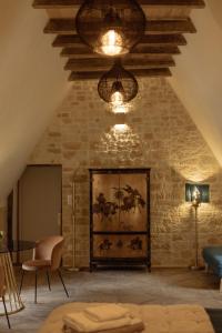 a living room with a stone wall and a chandelier at Manoir de Laroque Delprat in Autoire