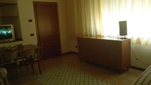 un salon avec une table et une télévision ainsi qu'une chambre avec un bureau dans l'établissement Rose Apartment, à Crotone