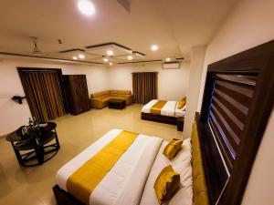 a hotel room with two beds and a couch at Thejaswini Residency Cheruvathur in Nīleshwar
