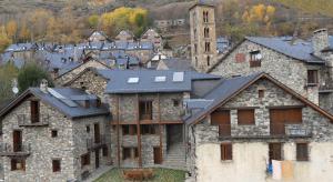 an old stone building with a tower in a town at Apartaments Ca de Badia in Taüll