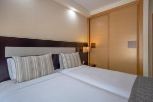 una camera da letto con un grande letto bianco con due cuscini di Areias Village Beach Suite Hotel ad Albufeira