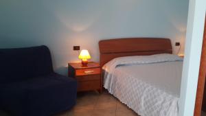 クロトーネにあるRose Apartmentのベッドルーム(ベッド1台、ランプ、椅子付)