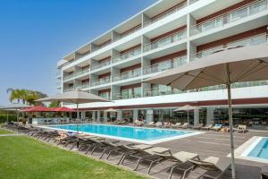 a hotel with a swimming pool with chairs and umbrellas at Areias Village Beach Suite Hotel in Albufeira