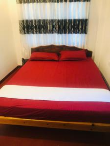 a bedroom with a red and white bed with a curtain at Villa Moon breeze Nilaveli in Trincomalee