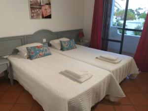 Un dormitorio con una cama blanca con toallas. en Sabine Apartamento T1 Superior en Albufeira