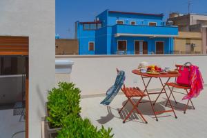 a table and chairs on a balcony with a blue building at Macramè Suites in Sciacca