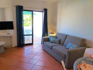 a living room with a couch and a sliding glass door at Sabine Apartamento T1 Superior in Albufeira