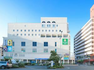 een groot wit gebouw met een bord erop bij Vessel Inn Yachiyo Katsudai Ekimae in Yachiyo