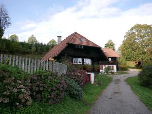 une maison avec une clôture à côté d'un chemin de terre dans l'établissement Schwarzwald Buchenhof, à Zell am Harmersbach