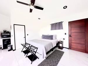 a white bedroom with a bed and a ceiling fan at Black & White Apartments Monteverde in Monteverde Costa Rica