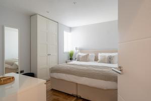 a white bedroom with a bed and a white cabinet at Bol Y Maer, Bude in Bude
