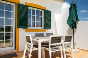 - une salle à manger avec une table, des chaises et un parasol vert dans l'établissement Casa Galé - Joia das Sesmarias 600mts praia, à Albufeira