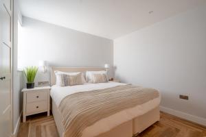 a white bedroom with a large bed and a nightstand at Bol Y Maer, Bude in Bude