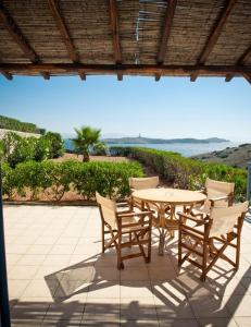 een tafel en stoelen op een patio met uitzicht op de oceaan bij Sunrise Beach Suites in Azolimnos