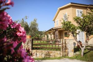 une maison avec une clôture et des fleurs roses dans l'établissement Bio Agriturismo Poggio Aione, à Saturnia