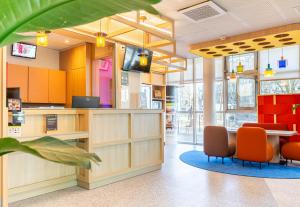 un bureau avec des chaises orange, un comptoir et une table dans l'établissement B&B HOTEL Nantes Centre, à Nantes