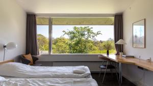 - une chambre avec un lit, un bureau et une fenêtre dans l'établissement Toppen af Ebeltoft, à Ebeltoft