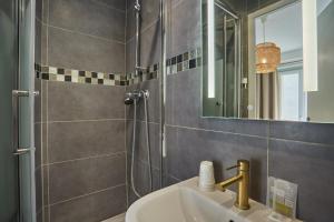 W łazience znajduje się umywalka oraz prysznic z lustrem. w obiekcie Hipotel Paris Gare du Nord Merryl w Paryżu