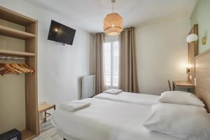 a hotel room with two beds and a window at Hipotel Paris Gare du Nord Merryl in Paris