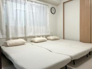 2 camas en una habitación con un reloj en la pared en The Emilio 102 Shinjuku newly renovated and opened in June 2024, en Tokio