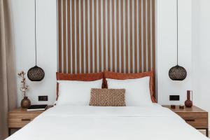 Verano Afytos Hotel في أفيتوس: غرفة نوم بسرير ابيض وجدار مخطط