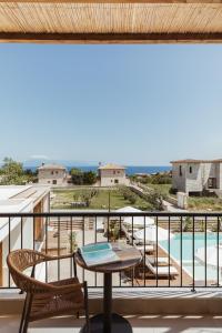 einen Balkon mit einem Tisch und Poolblick in der Unterkunft Verano Afytos Hotel in Afytos