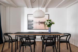 a dining room table with black chairs and a vase with flowers at Kings Square apartments by Daniel&Jacob's in Copenhagen