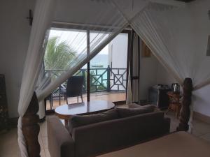 a living room with a couch and a view of the ocean at Langi Langi Beach Bungalows in Nungwi
