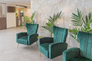 two green chairs in a room with plants at Palangos Vetra in Palanga