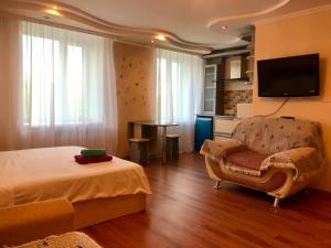 a bedroom with a bed and a chair and a television at City Center - Nurken Abdirova 32 in Karagandy