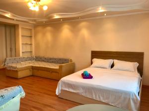 a bedroom with a bed and a bench with a hat on it at City Center - Nurken Abdirova 32 in Karagandy