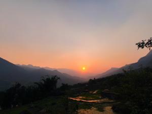 um pôr do sol nas montanhas com o pôr do sol em Sapa Pomu Home em Sa Pa