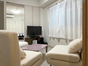 un soggiorno con 2 sedie e una TV a schermo piatto di The Emilio 102 Shinjuku newly renovated and opened in June 2024 a Tokyo
