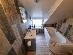 a bathroom with a tub and a sink and a bath tub at Trinket - The Cliff Top Cottage in Sewerby +29 photos