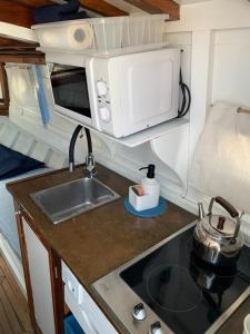 uma cozinha com um lavatório e um micro-ondas em Lovely wooden boat in Port forum, with AC and two bikes. em Barcelona