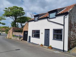 a white house with a blue door on a street at Trinket - The Cliff Top Cottage in Sewerby